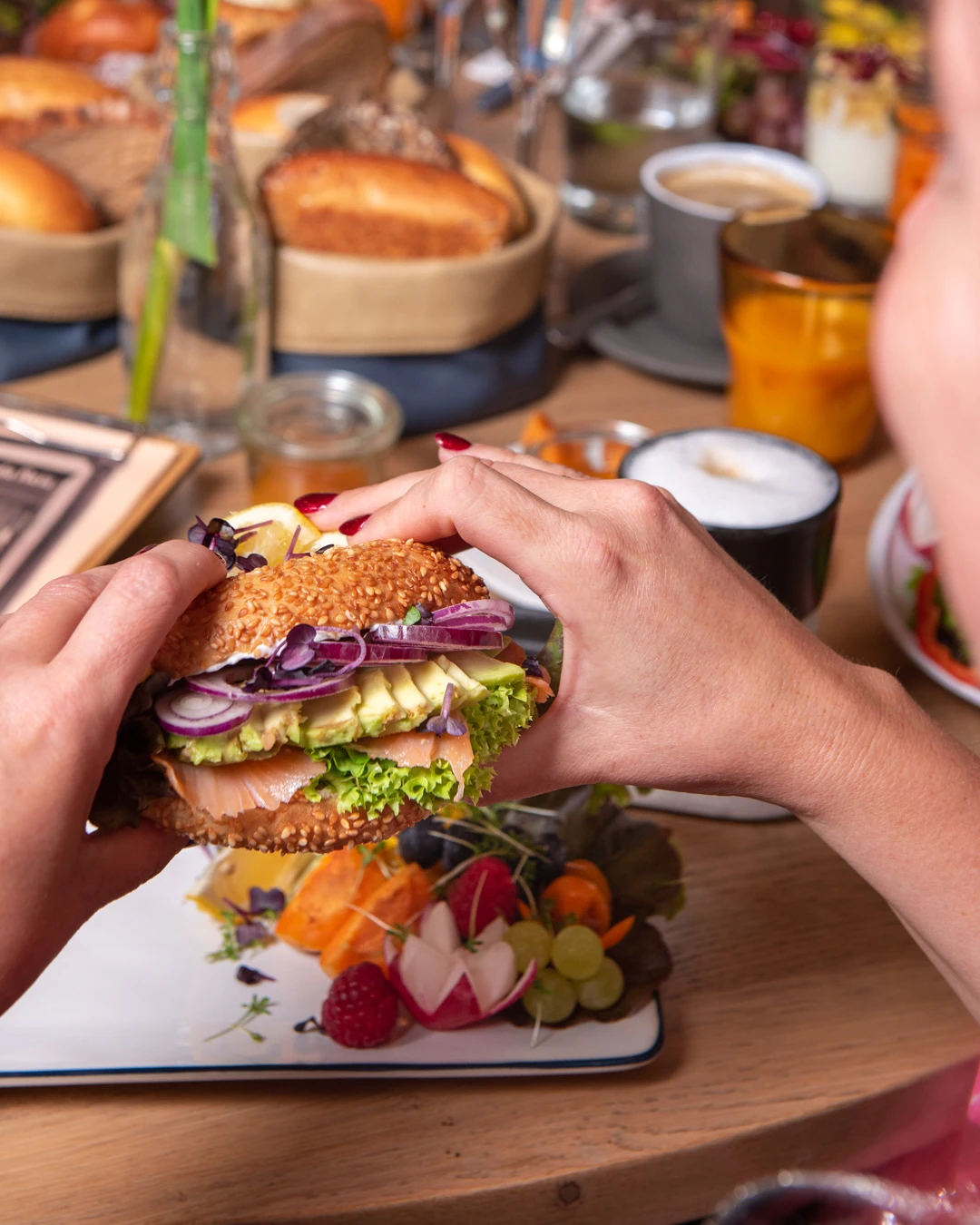 Gast genießt einen Sesam-Bagel mit Lachs, Avocado und Zwiebeln im Café Reis Gilching