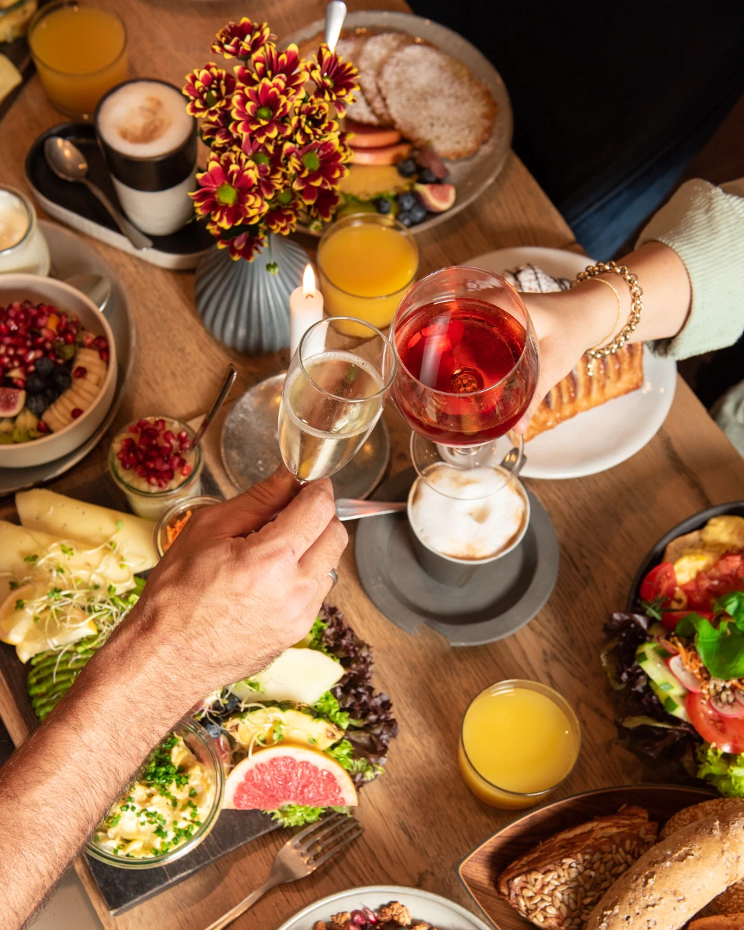 Zwei Gäste stoßen mit Sekt und Rosé an einem reichhaltigen Brunch-Tisch im Café Reis Gilching an