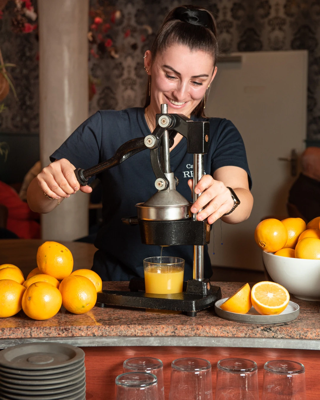 Mitarbeiterin presst im Café Reis Gilching frischen Orangensaft mit der Handpresse