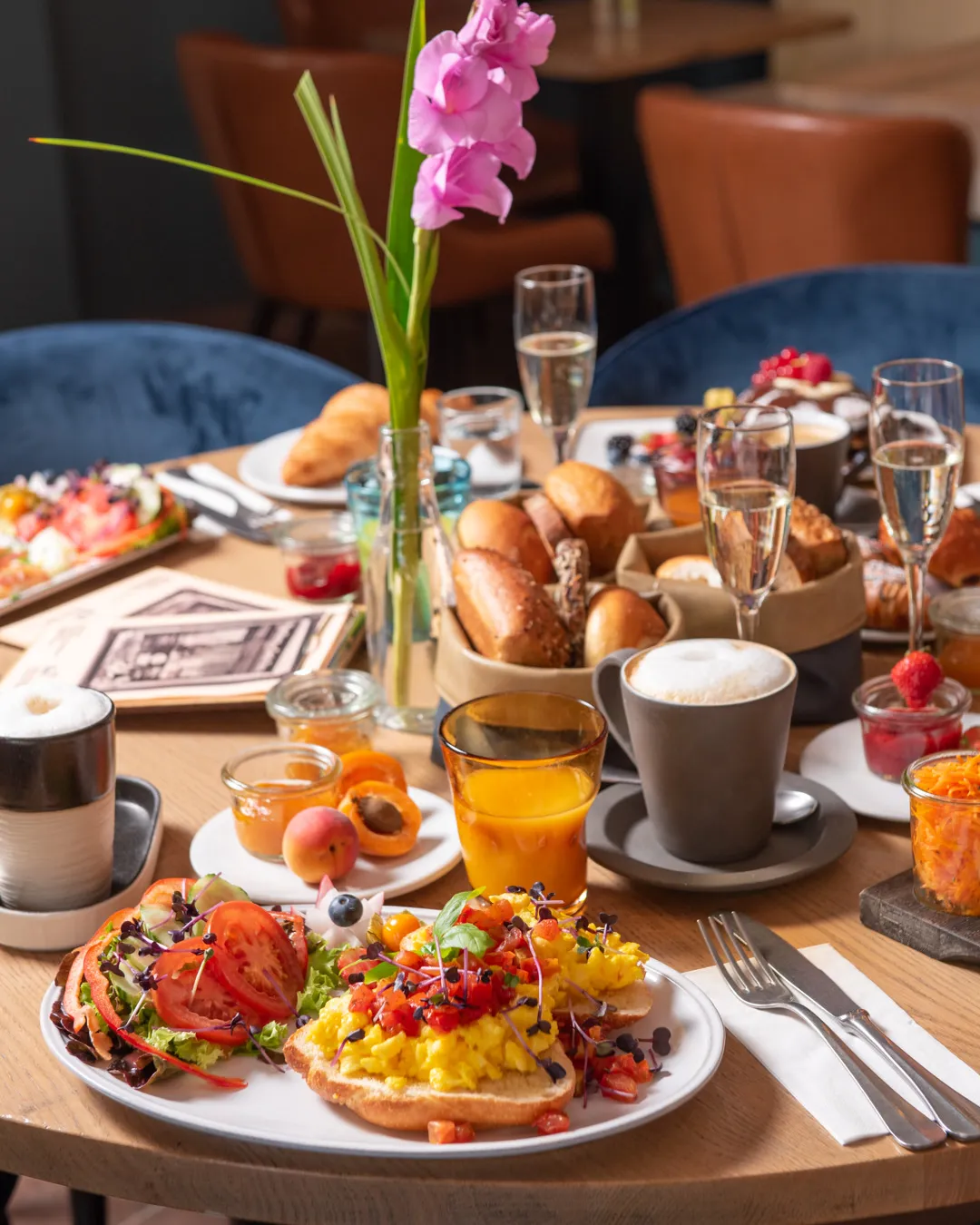 Gedeckter Frühstückstisch im Café Reis Gilching mit Rührei-Bruschetta, Brotkorb, Cappuccino, Prosecco und Gladiole