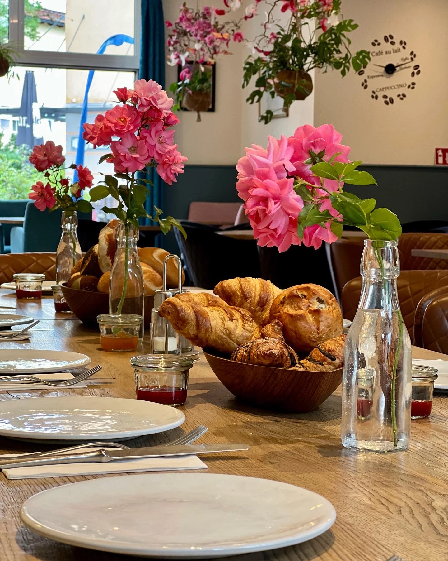 Gedeckter Frühstückstisch im Café Reis Gilching mit Croissants, rosa Rosen und Marmelade im Morgenlicht