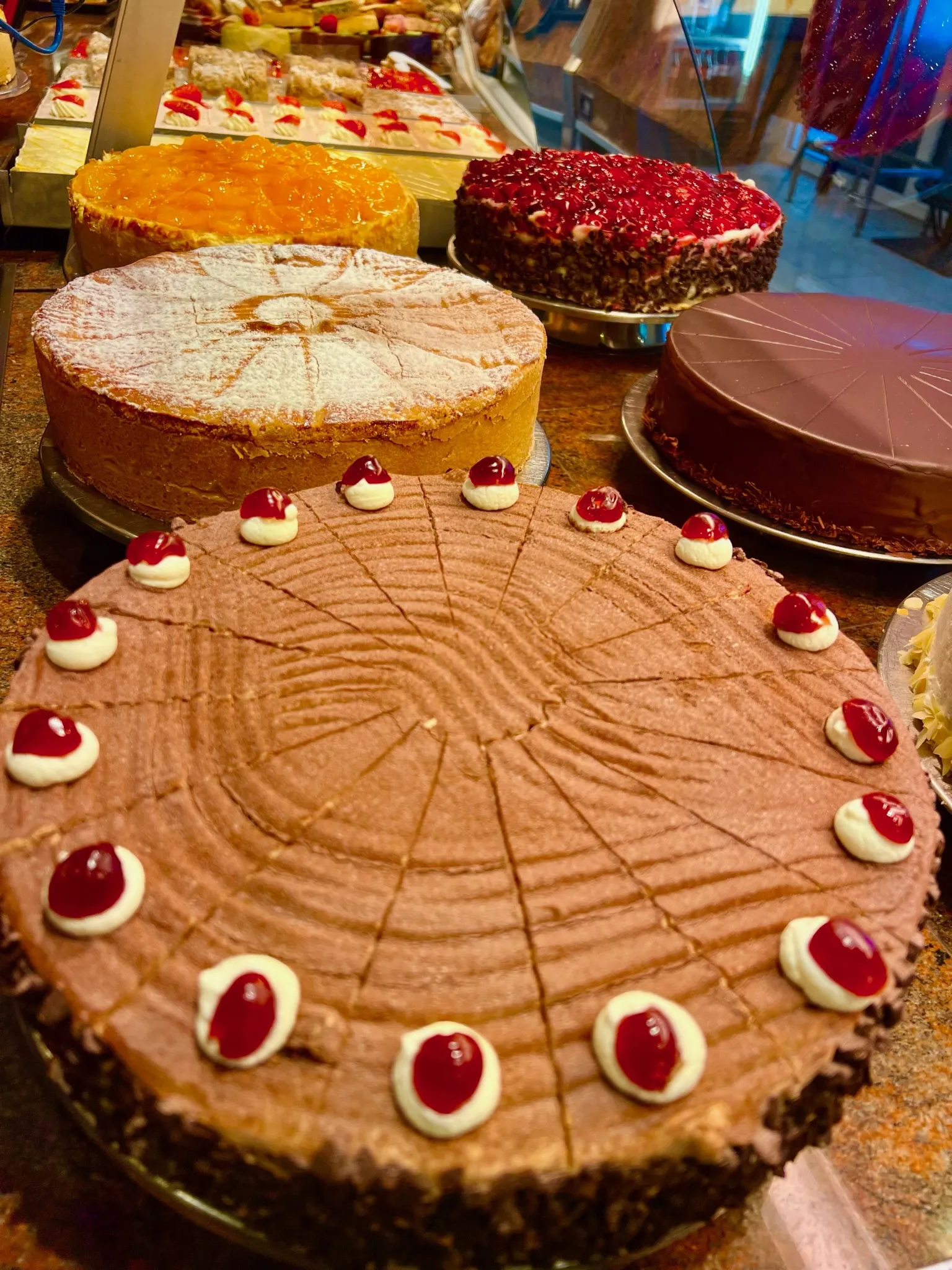 Tortenauswahl in der Auslage des Café Reis Gilching mit Schokoladentorte, Sanddorntorte, Himbeertorte und Apfelkuchen